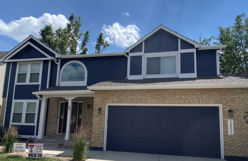 Exterior Two-story brick and navy blue house with a double garage, white trim, and a covered entryway; address number 3855 visible by the garage. Recently refreshed by a professional painting contractor from Colorado Springs, the home features vibrant exterior finishes that enhance its curb appeal.